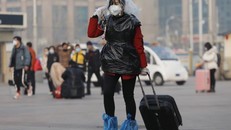 Một nữ hành khách ở ga tàu hỏa Bắc Kinh dùng túi nylon che đầu, chân và thân để phòng virus corona chủng mới Covid-19. - Ảnh: EPA.