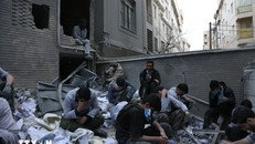 Người dân ngồi trên đống đổ nát của những tòa nhà bị phá hủy do xung đột tại Tehran, Iran ngày 15/3/2026. Ảnh: THX/TTXVN