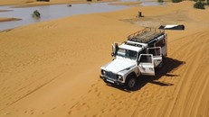 Một chiếc xe chở khách du lịch trên những cồn cát bên cạnh một hồ nước do mưa lớn gây ra ở thị trấn sa mạc Merzouga. Ảnh: AP