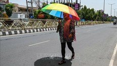 Người dân che ô khi di chuyển ngoài trời trong ngày nắng nóng tại Amritsar, Ấn Độ. Ảnh: AFP/TTXVN