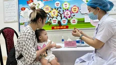 Phụ huynh cho trẻ đến trạm y tế để bổ sung Vitamin A.