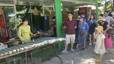 Du khách thích thú với nghệ thuật đàn đá biểu diễn tại khu vực hàng lưu niệm thuộc di tích quốc gia đặc biệt Tháp Nhạn. Ảnh: Tường Quân/TTXVN.