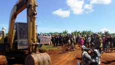 Người vây quanh chiếc máy múc ngăn chặn không cho nhà thầu thi công