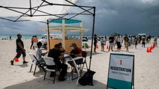 Mọi người đăng ký tiêm chủng vaccine ngừa COVID-19 tại một bãi biển ngày 9/5. (Ảnh: AFP-Yonhap)