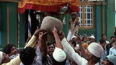 Hòn đá bay cao khi 11 người đàn ông cùng chạm tay vào và đọc tên vị thánh.