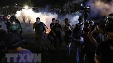 Người biểu tình xung đột với cảnh sát trong cuộc tuần hành phản đối vụ cảnh sát bắn người da màu tại Kenosha, bang Wisconsin (Mỹ). (Ảnh: AFP/TTXVN)