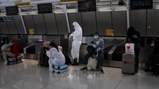 Hành khách đeo khẩu trang và mặc đồ bảo hộ phòng lây nhiễm COVID-19 tại sân bay John F. Kennedy ở Queens, New York, Mỹ. Ảnh tư liệu: AFP/TTXVN