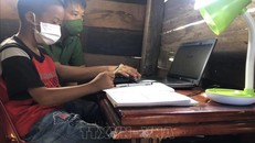 Thiếu tá Lê Anh Tuấn, Đội tổng hợp Công an huyện Cư M’Gar hướng dẫn học sinh có hoàn cảnh khó khăn sử dụng laptop do anh trao tặng. Ảnh minh họa: TTXVN phát.