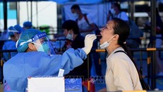 Nhân viên y tế lấy mẫu xét nghiệm COVID-19 cho người dân tại tỉnh Quảng Đông, Trung Quốc. Ảnh: AFP/TTXVN