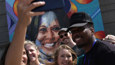 Mọi người chụp ảnh tự sướng trước bức tranh tường có hình ứng cử viên tổng thống đảng Dân chủ, Phó Tổng thống Kamala Harris.