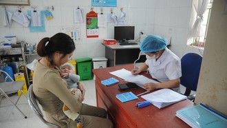 Nhân viên y tế khám sàng lọc, kiểm tra tình trạng của trẻ trước khi tiêm vaccine. Ảnh: Vũ Quang/TTXVN.