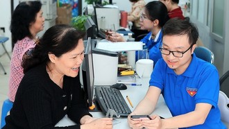 Đoàn viên thanh niên phường Hàng Bồ (quận Hoàn Kiếm, thành phố Hà Nội) hỗ trợ người dân thực hiện thủ tục hành chính công trên thiết bị điện thoại thông minh. Ảnh: Phạm Hậu/TTXVN.