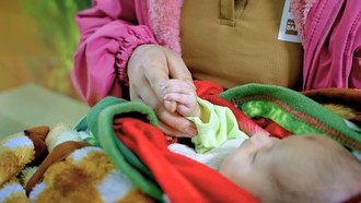 Bé H.T.P. ngủ yên trong vòng tay mẹ vào ngày tái khám
