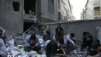 Người dân ngồi trên đống đổ nát của những tòa nhà bị phá hủy do xung đột tại Tehran, Iran ngày 15/3/2026. Ảnh: THX/TTXVN