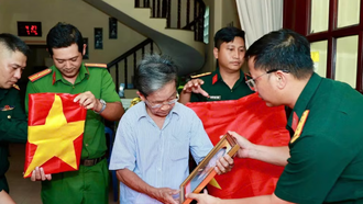 Ông Phan Văn Tư xúc động bên di ảnh hai người anh trai đã hy sinh. (Ảnh: Bộ Tư lệnh Thành phố Hồ Chí Minh cung cấp)