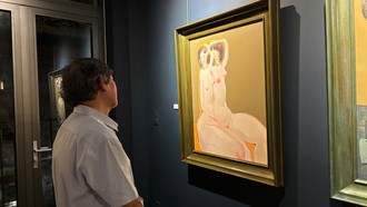 Một nhà sưu tập đang xem tranh trong triển lãm "Sắc thân". Ảnh: TRÀ TRƯƠNG