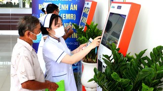 Nhân viên y tế hướng dẫn người dân đăng ký khám bệnh qua hệ thống kios tự động tại Bệnh viện Đa khoa Trà Vinh, tỉnh Vĩnh Long. Ảnh: TTXVN.