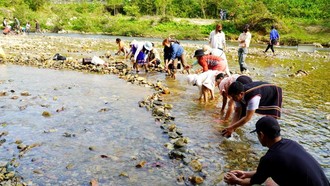 Người dân tập trung về khu vực sông Trường, bê đá đắp đập ngăn dòng chảy để bắt cá.