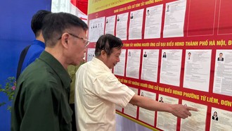 Cử tri và cán bộ trong tổ bầu cử tham khảo danh sách các đại biểu. 