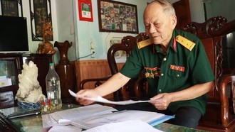 Cựu chiến binh Nguyễn Thanh Bình cẩn thận ghi chép, lưu giữ thông tin tên, ngày hy sinh, đơn vị chiến đấu, quê quán, thân nhân các liệt sỹ. (Ảnh: Tường Vi/TTXVN)