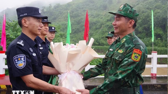 Đại diện chỉ huy trưởng tuần tra hai bên tặng hoa cho nhau tại vạch phân định cầu hữu nghị biên giới Việt-Trung. (Ảnh: TTXVN phát)