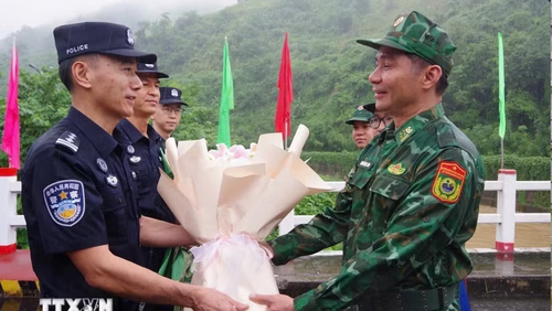 Đại diện chỉ huy trưởng tuần tra hai bên tặng hoa cho nhau tại vạch phân định cầu hữu nghị biên giới Việt-Trung. (Ảnh: TTXVN phát)