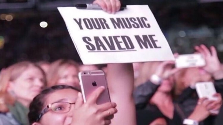 Một người hâm mộ giơ cao tấm biển ghi “Âm nhạc của bạn đã cứu lấy tôi” trong một buổi hòa nhạc.