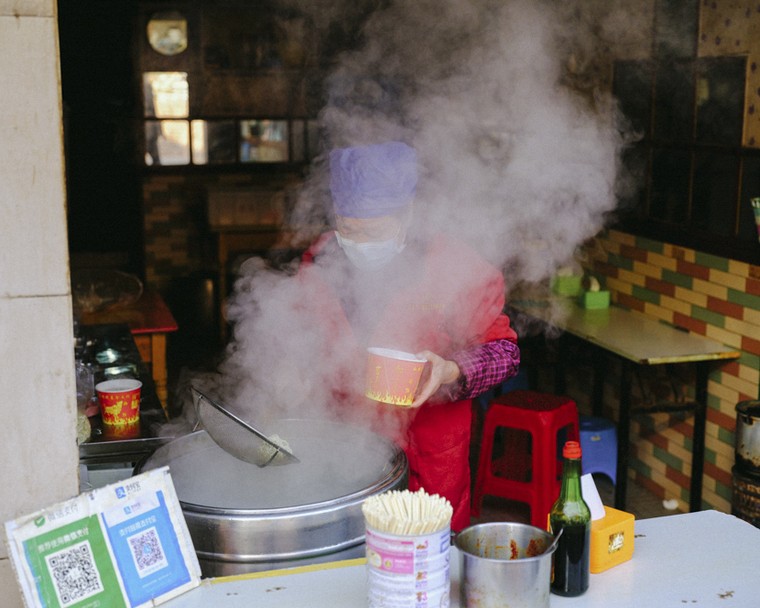 A woman prepares “hot and dry noodles,” a local culinary specialty, at a breakfast stall in Wuhan, Hubei province, April 8, 2020. Shi Yangkun/Sixth Tone