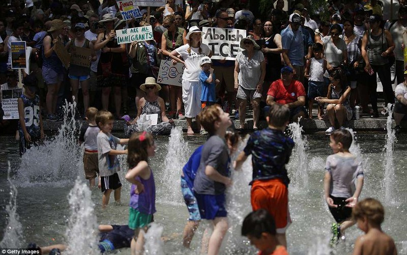 Saturday, thousands of organizers across the country protesting the Trump administration's 'zero tolerance' policy baked in the heat. Organizers are pictured cooling off at a fountain in ChicagoÂ