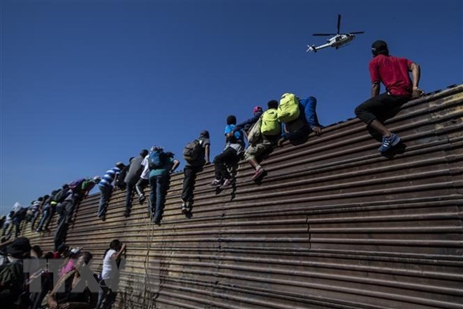 Người di cư vượt qua bức tường biên giới Mỹ-Mexico ở gần cửa khẩu El Chaparral, Tijuana, bang Baja California, Mexico ngày 25/11/2018. (Nguồn: AFP/TTXVN)