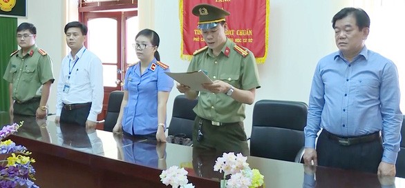 Ông Hoàng Tiến Đức (bìa phải) - giám đốc Sở GD-ĐT tỉnh Sơn La - chứng kiến cơ quan điều tra tống đạt quyết định khởi tố và lệnh bắt tạm giam ông Lò Văn Huynh, trưởng Phòng khảo thí và quản lý chất lượng Sở GD-ĐT tỉnh Sơn La - Ảnh cắt từ clip