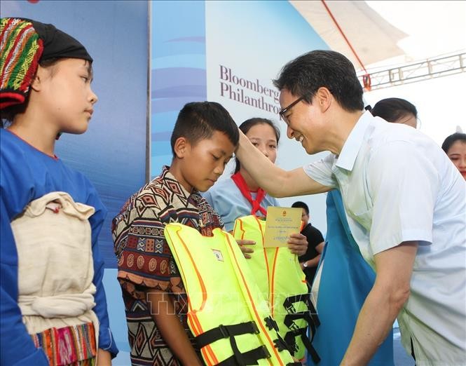 Phó Thủ tướng Chính phủ Vũ Đức Đam tặng áo phao cho các em nhỏ tại buổi lễ. Ảnh: Thanh Tùng/TTXVN