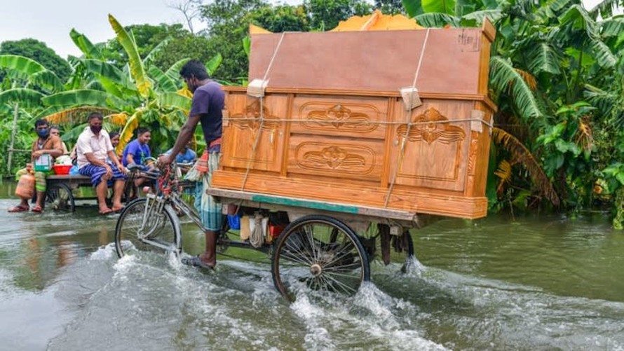 Một người đàn ông lội xe qua vùng nước lũ gần thủ đô Dhaka của Bangladesh.