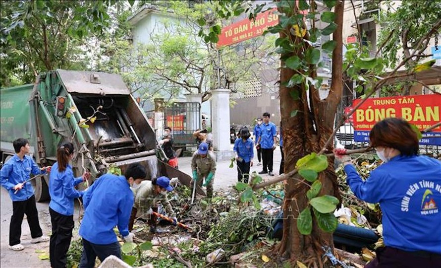 Đoàn viên, thanh niên quận Hoàng Mai cùng công nhân vệ sinh môi trường thu gom cành cây gãy đổ do bão số 3. 