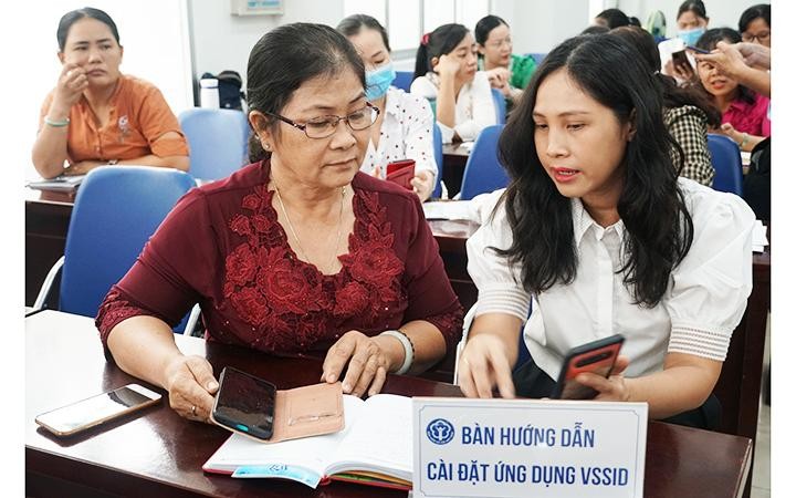 Cán bộ BHXH thành phố Hồ Chí Minh tư vấn, hướng dẫn người dân cài đặt và sử dụng ứng dụng VssID. Ảnh: TRUNG TÂM