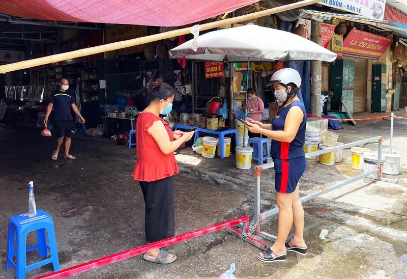 Cổng được chặn bằng khung sắt, nhiều người đi xe đứng ngoài chờ người bán mang hàng ra. Nhiều người chọn phương thức thanh toán qua chuyển khoản nhằm tránh lây lan dịch bệnh. (Ảnh: Kinh tế & Đô thị)