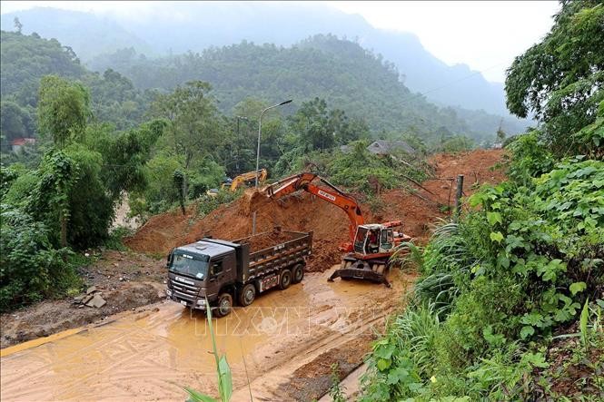  Các lực lượng chức năng khẩn trương giải phóng đất, đá để thông tuyến đường 435. Ảnh: Thanh Hải/TTXVN