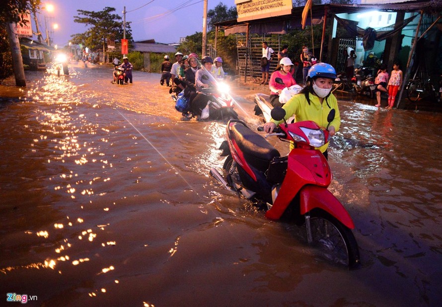 Đoàn người dắt bộ xe về nhà trong cảnh nước ngập nửa bánh