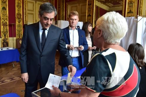 Ứng cử viên Jean-Luc Melenchon (phải) bỏ phiếu tại một địa điểm bầu cử ở Paris ngày 23/4. Ảnh: EPA/TTXVN