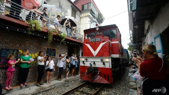 Du khách hứng thú với cảm giác đứng sát đoàn tàu khi tàu hỏa chạy qua - Ảnh: AFP