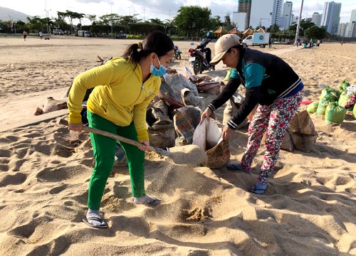 Người dân xúc đất trên bãi biển Nha Trang để chằng chống nhà cửa. Ảnh: Xuân Ngọc.