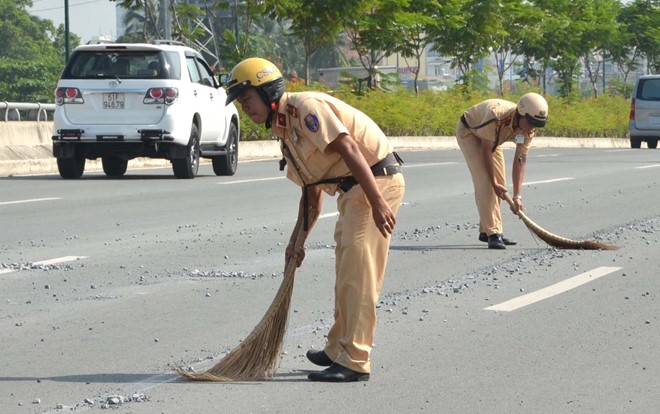 Cảnh sát giao thông quét dọn đá dăm trên đường Phạm Văn Đồng. 