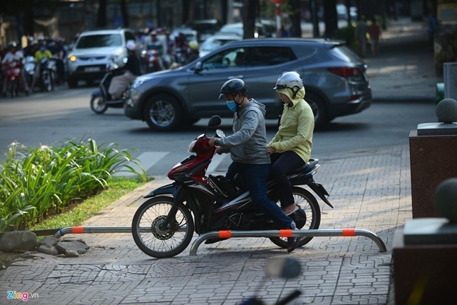 Dù gắn barie nhưng người dân đi xe máy vẫn cố leo lên vỉa hè.