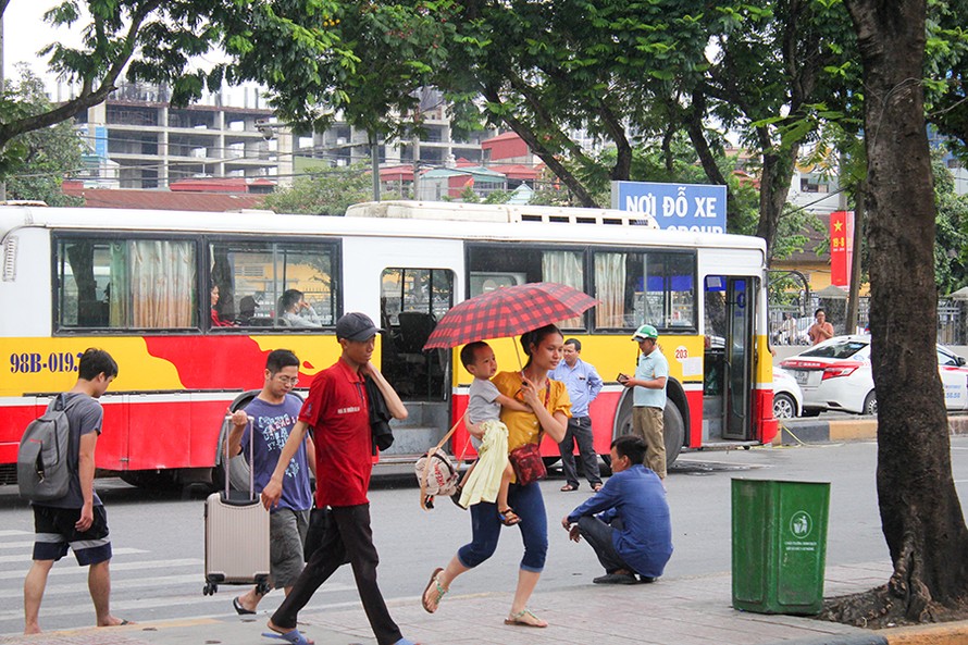 Một gia đình khẩn trương chạy vào bến xe khi trời mưa to. 