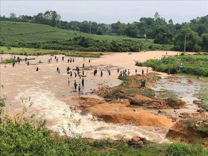 Nước chảy mạnh xuống vùng hạ du gây ngập, nhưng bất chấp nguy hiểm cảnh báo, nhiều người dân vẫn đổ xô đến để bắt cá. Ảnh: TTXVN