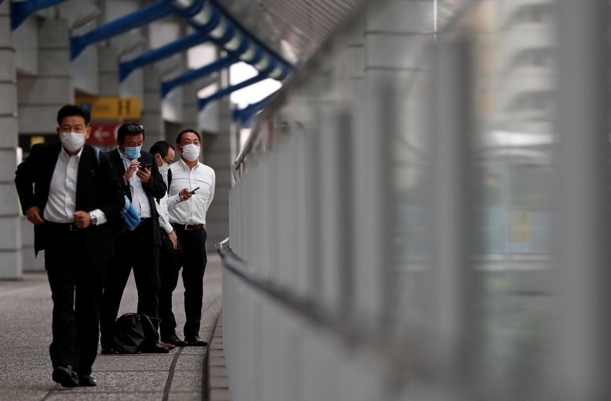 Nhân viên công sở đeo khẩu trang tại một cầu đi bộ ở Tokyo, Nhật Bản. Ảnh: REUTERS