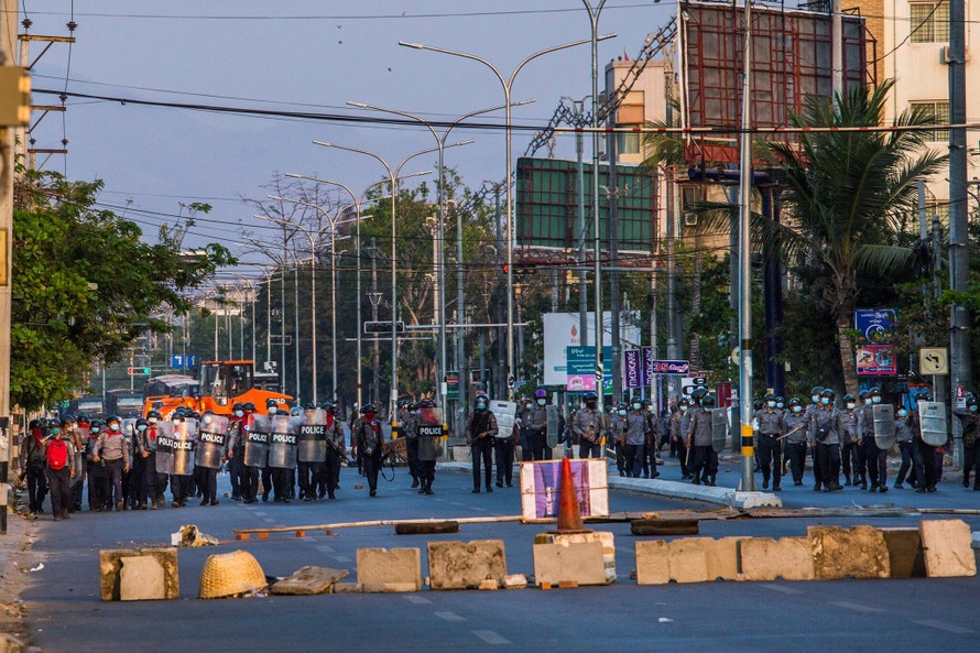 Lực lượng an ninh ở Mandalay chuẩn bị bước qua rào chắn do người biểu tình dựng lên. Ảnh: NY Times