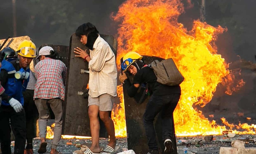 Người biểu tình tại Yangon núp sau các tấm khiên chắn. Ảnh: AFP