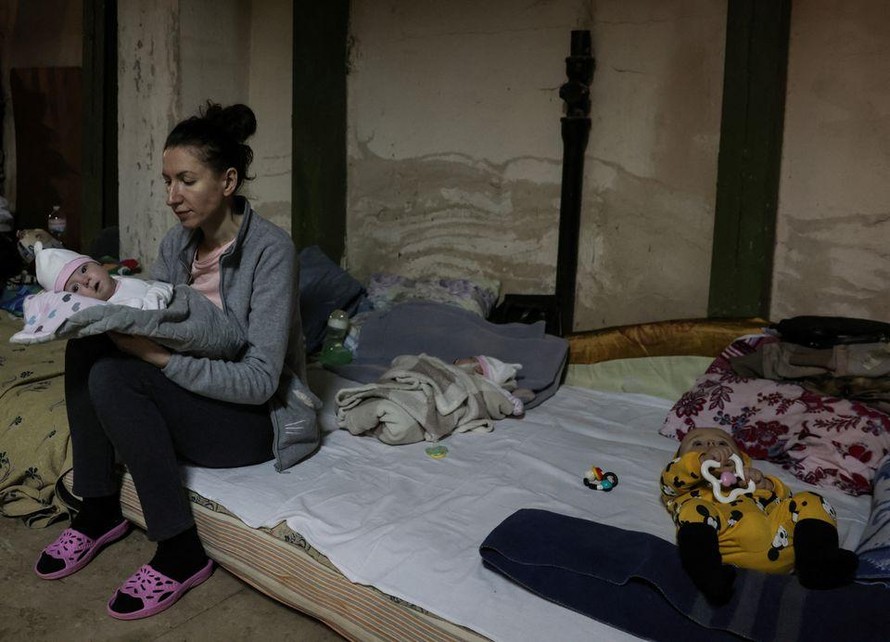 Một bà mẹ bế con ngồi trên nệm trong hầm trú ẩn của Bệnh viện Nhi Okhmadet. Ảnh: Reuters