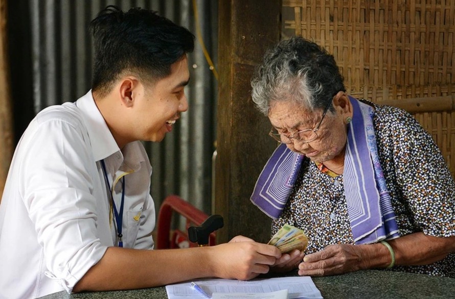 Cán bộ bưu điện chi trả lương hưu, trợ cấp tại nhà cho người già yếu không có khả năng đến nhận. Ảnh: CTV/Vietnam+